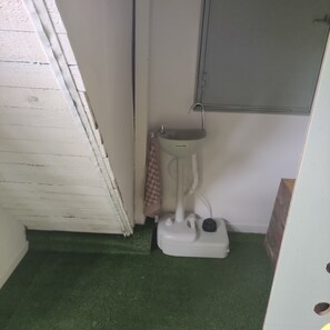 Une petite salle de bain avec des toilettes blanches, un carrelage vert et un meuble au-dessus du lavabo.