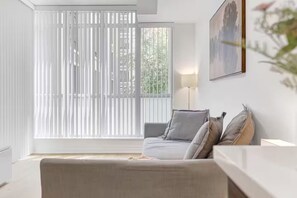 Un salon moderne avec un canapé, une lampe et un tableau accroché au mur.