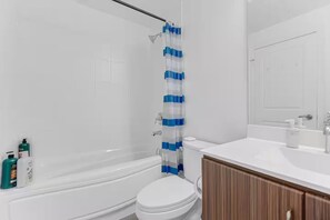 Une salle de bain avec une baignoire, des toilettes et un rideau de douche.