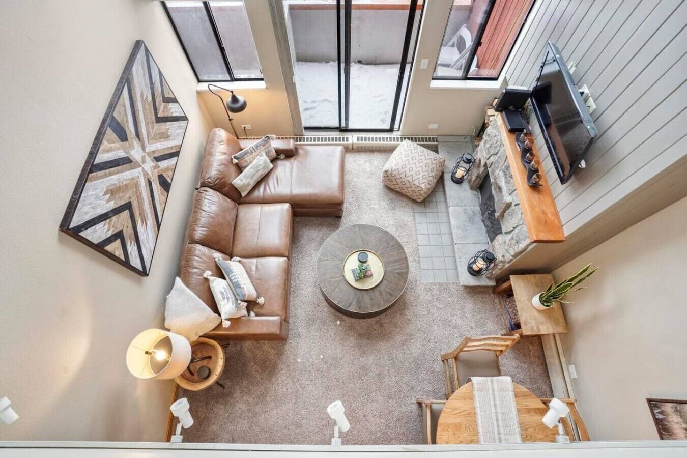 A high-ceilinged living room with a sectional sofa, a coffee table, and a fireplace.