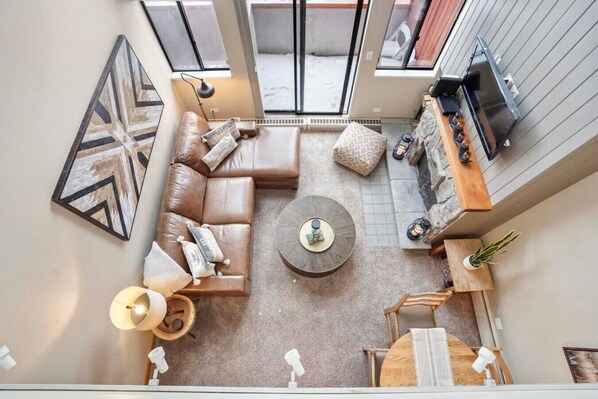 Ein Wohnzimmer mit hohen Decken, einem Ecksofa, einem Couchtisch und einem Kamin.