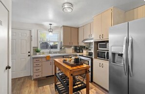 A modern kitchen with stainless steel appliances, wooden cabinets, and a central island. - Beautiful 3-bedroom house with hot tub in peaceful Downtown Loveland (Loveland)