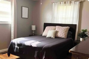 A bedroom with a bed, a bedside lamp, a window with curtains, and a small plant on a table. - Beautiful 3-bedroom house with hot tub in peaceful Downtown Loveland (Loveland)