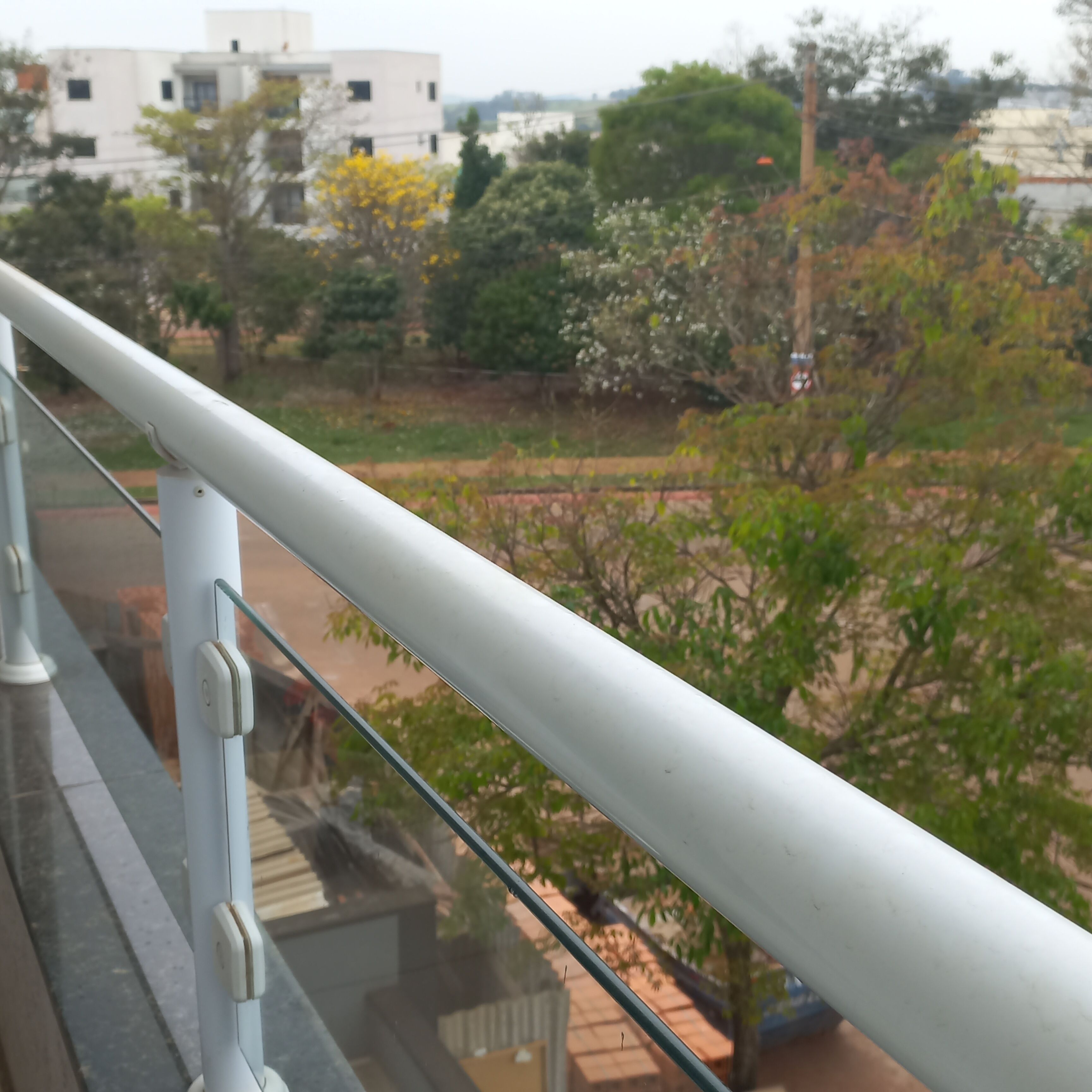 A balcony railing with a view of a residential area, including houses and trees.