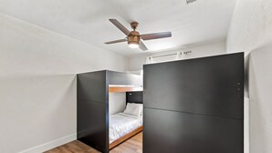 Habitación pequeña con literas, ventilador de techo y armario.