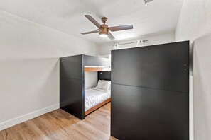 Habitación pequeña con literas, ventilador de techo y armario.