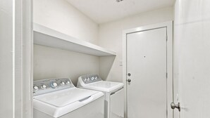Un cuarto de lavandería con dos lavadoras blancas y un lavabo.