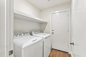Un cuarto de lavandería con dos lavadoras blancas y un lavabo.