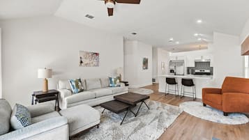 A modern living room with a sofa, coffee table, and a dining area with chairs.
