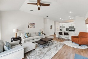 Uma sala de estar moderna com sofá, mesa de centro e área de jantar com cadeiras.