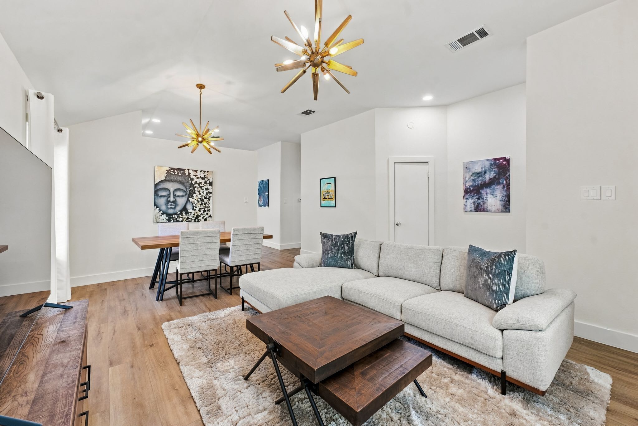 A modern living room with a sectional sofa, a coffee table, and a dining area with chairs.