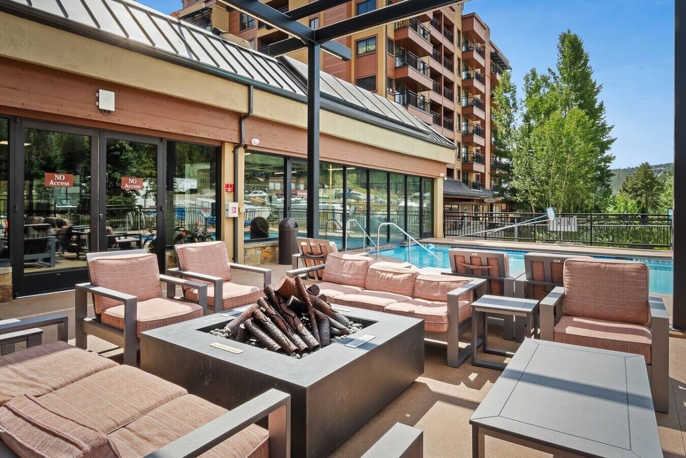 Eine Dachterrasse mit Sitzgelegenheiten im Freien, einer Feuerstelle und einem Pool.