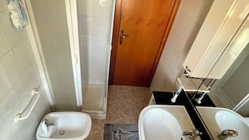 Ein Badezimmer mit zwei Waschbecken, einer Dusche und einer Toilette.