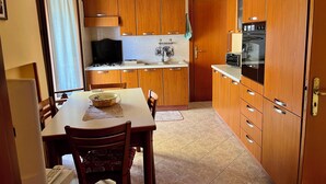 Une cuisine compacte avec des meubles en bois, une table à manger, des chaises, une cuisinière et un four encastré.