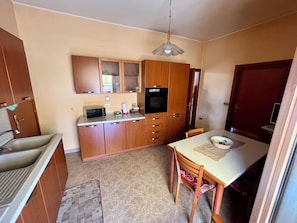 Une cuisine compacte avec des meubles en bois, un four encastré, un four à micro-ondes et une table à manger avec des chaises.