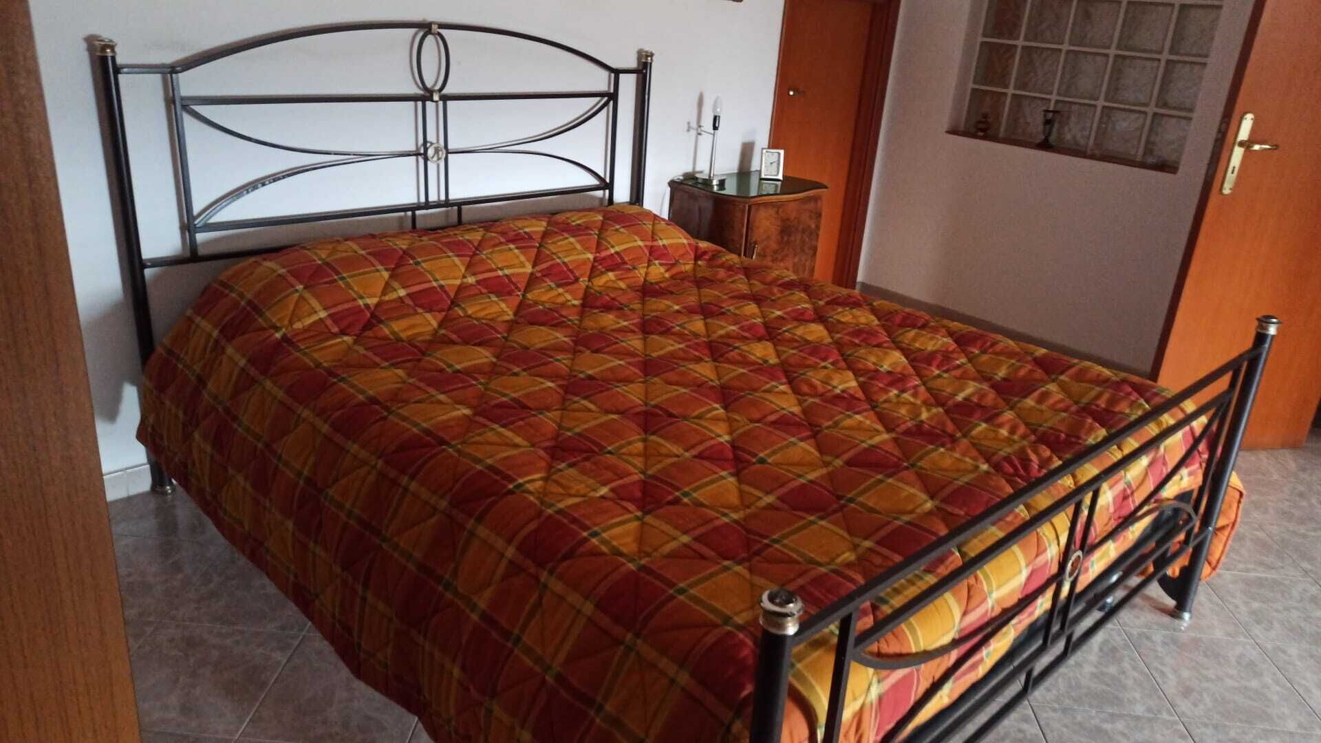 Un letto con struttura in metallo e copripiumino trapuntato.