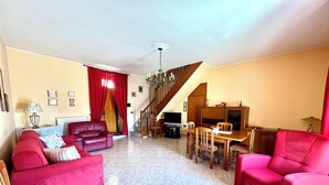 Un vaste espace de vie comprenant une table à manger, des canapés rouges et un escalier menant à un niveau supérieur.