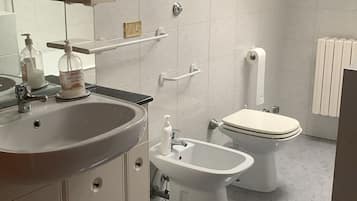 Un bany modern amb un rentapans, mirall, vàter, bidet i un fanal.