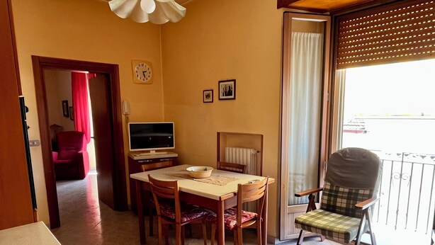 Un espace repas comprenant une table, des chaises, un téléviseur et une fenêtre donnant sur un paysage agréable.