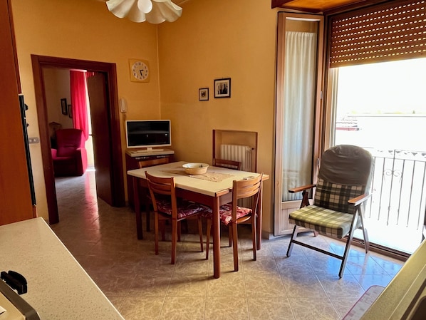 Un comedor con una mesa, sillas, un televisor y un ventanal con vistas.