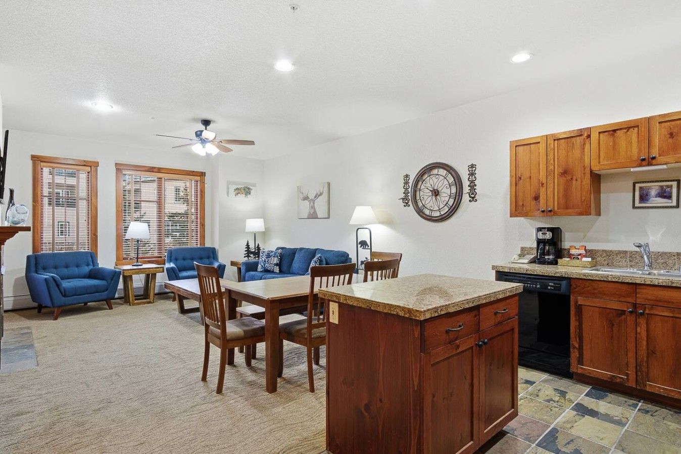 A spacious living room with a dining area, wooden cabinets, and a kitchen with granite countertops.