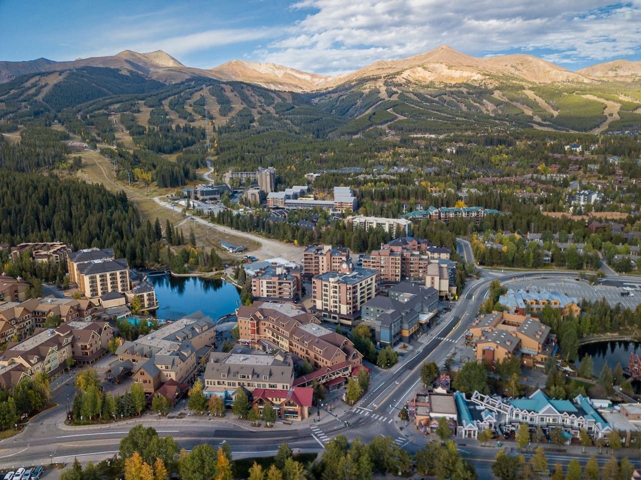 A town with a central roundabout, buildings with flat roofs, and a lake.