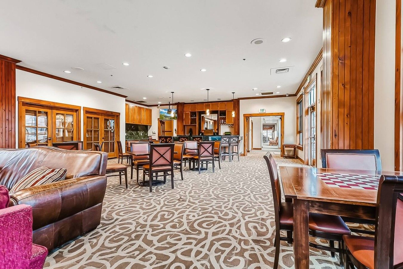 Un hall d’hôtel avec un tapis à motifs, des meubles en bois et un coin bar.