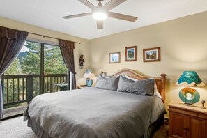 Ein Schlafzimmer mit einem Bett, einem Deckenventilator, einem Fenster mit Vorhängen und einem Balkon.