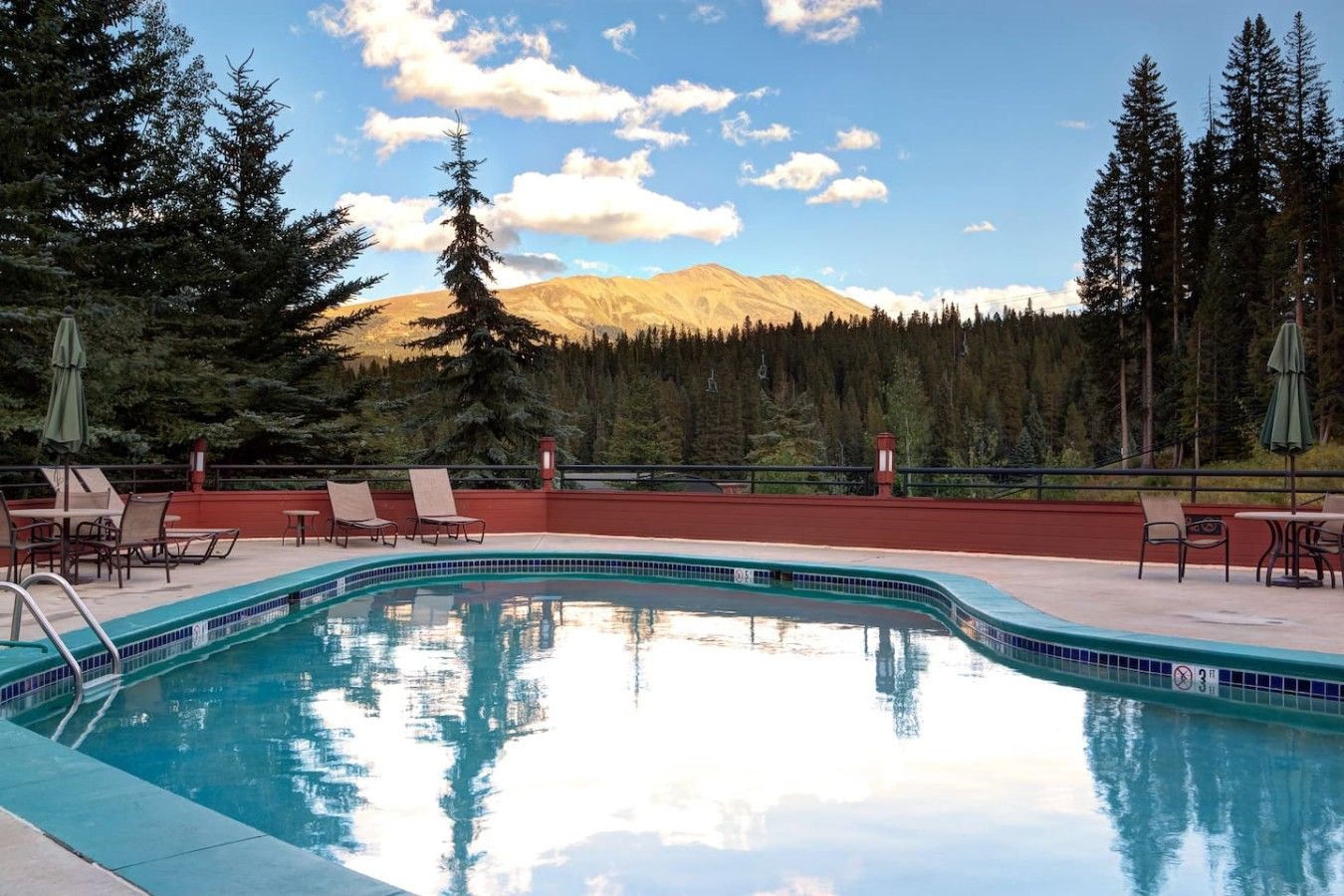 A pool with lounge chairs and a mountain view.