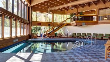 Una piscina interior con revestimiento de madera, una escalera y zonas de estar.