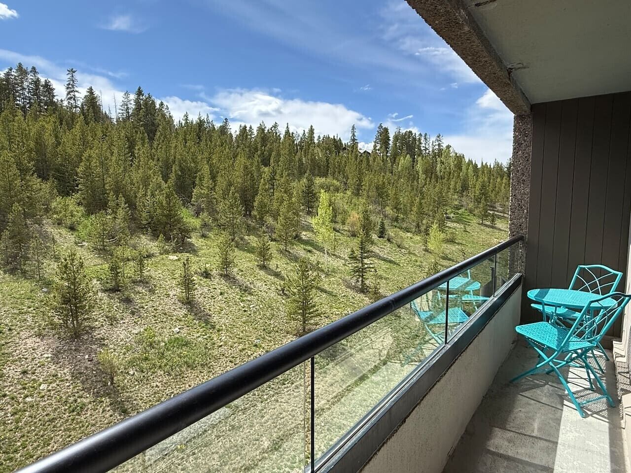 Un balcon doté d’une balustrade en verre, d’une table et de deux chaises.
