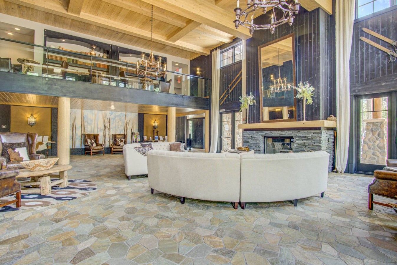 A spacious living area with a stone floor, a fireplace, and a high ceiling with wooden beams.