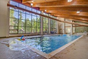 An indoor swimming pool with clear glass walls, wooden beams, and a view of trees outside. - 5 minutes from Keystone Resort with Hot Tub & Pool (Keystone)