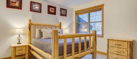 Un dormitorio con cama de madera, mesitas de noche, cómoda y cuadros enmarcados en la pared.