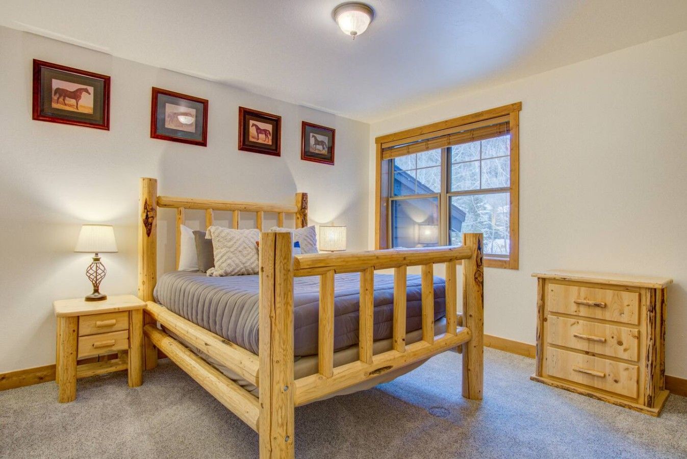 Un dormitorio con una cama de madera, mesitas de noche, un aparador y cuadros enmarcados en la pared.