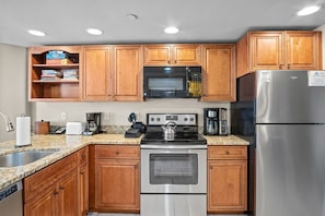A kitchen with wooden cabinets, a stainless steel refrigerator, a microwave, a stove, and a coffee maker. - 1 Bedroom True Ski-in/out in Beaver Run Building 4 (Breckenridge)