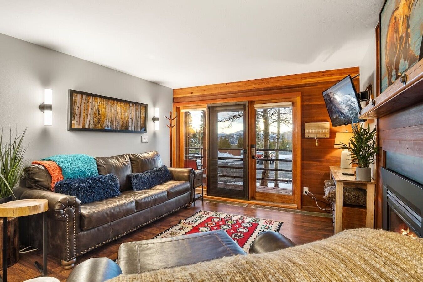 A modern living room with a leather sofa, a wooden coffee table, and a large window with a view of the outdoors.