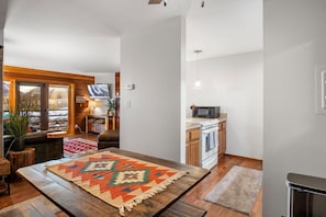 Een gezellige woonkamer met een houten tafel, een vloerkleed met patroon en een televisie.