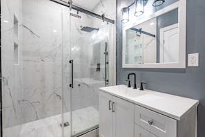 Une salle de bain moderne avec une douche à parois de verre, un lavabo blanc et un grand miroir.