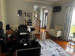 A home office with a desk, printer, and computer, a bookshelf, a couch, and a staircase leading to another room. - Jamestown 4BR Estate (Jamestown)