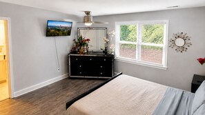 A bedroom with a bed, dresser, TV, window, and ceiling fan. - Jamestown 4BR Estate (Jamestown)