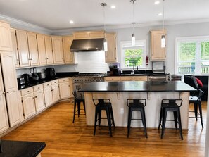 Een moderne keuken met houten kastjes, een centraal kookeiland met barkrukken en een grote kookplaat.