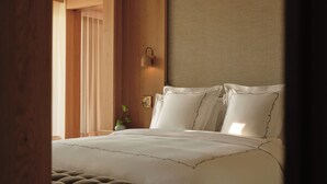 A bedroom with a large bed, a wooden headboard, and a window with curtains.
