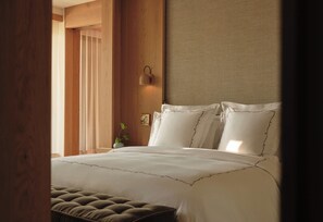 A bedroom with a large bed, a wooden headboard, and a window with curtains. - Rosewood Calistoga (Calistoga)