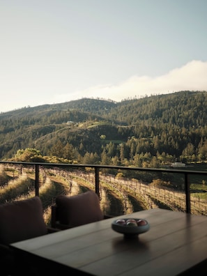 A terrace with a view of a forested hillside, a table with a bowl, and a chair. - Rosewood Calistoga (Calistoga)
