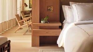 A bedroom with a bed, a wooden nightstand, a chair, and a desk.