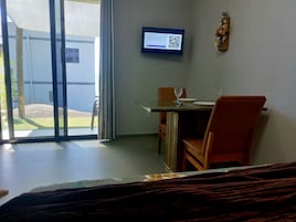 Una habitación de hotel con una cama, un escritorio con una silla, un televisor montado en la pared y una ventana con vistas al exterior.