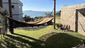 Un hamac installé dans un endroit ombragé, avec vue sur la mer et les montagnes.