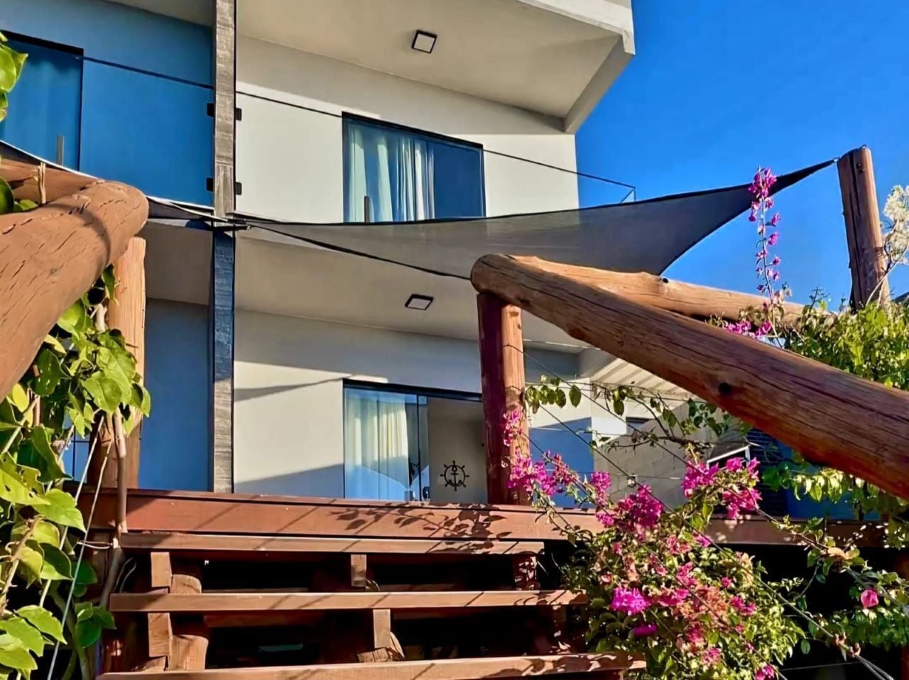 Um edifício moderno com varanda, guarda-corpos de madeira e vista para o céu.