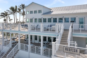 A multi-story building with outdoor seating areas and a sign indicating a Redfish Grill. - Beachfront Gulf Cottage w/ Panoramic Gulf Views (Captiva)